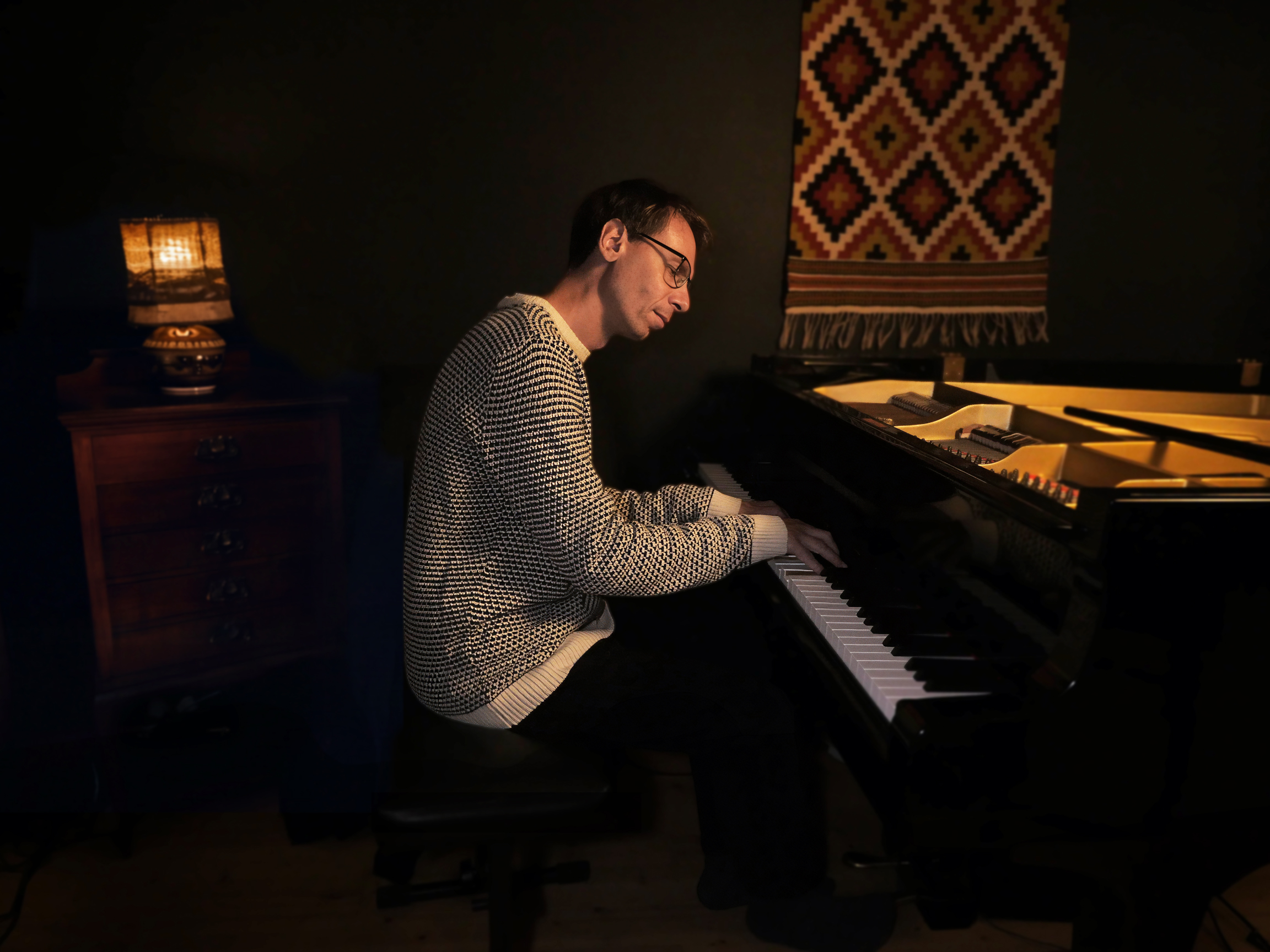 Si Lund playing a grand piano in a warmly lit room